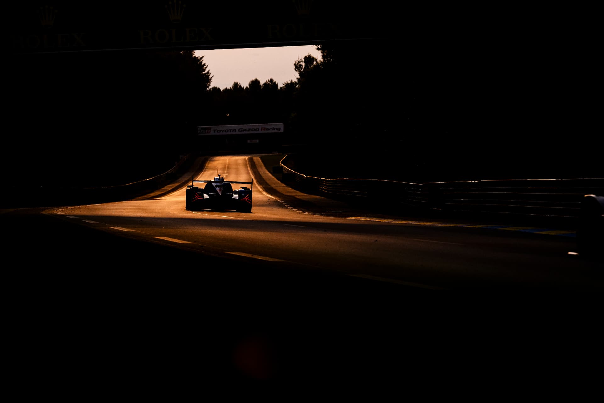 Hypercar in silhouette on the run to Indianapolis at sunset, under the Rolex banner.